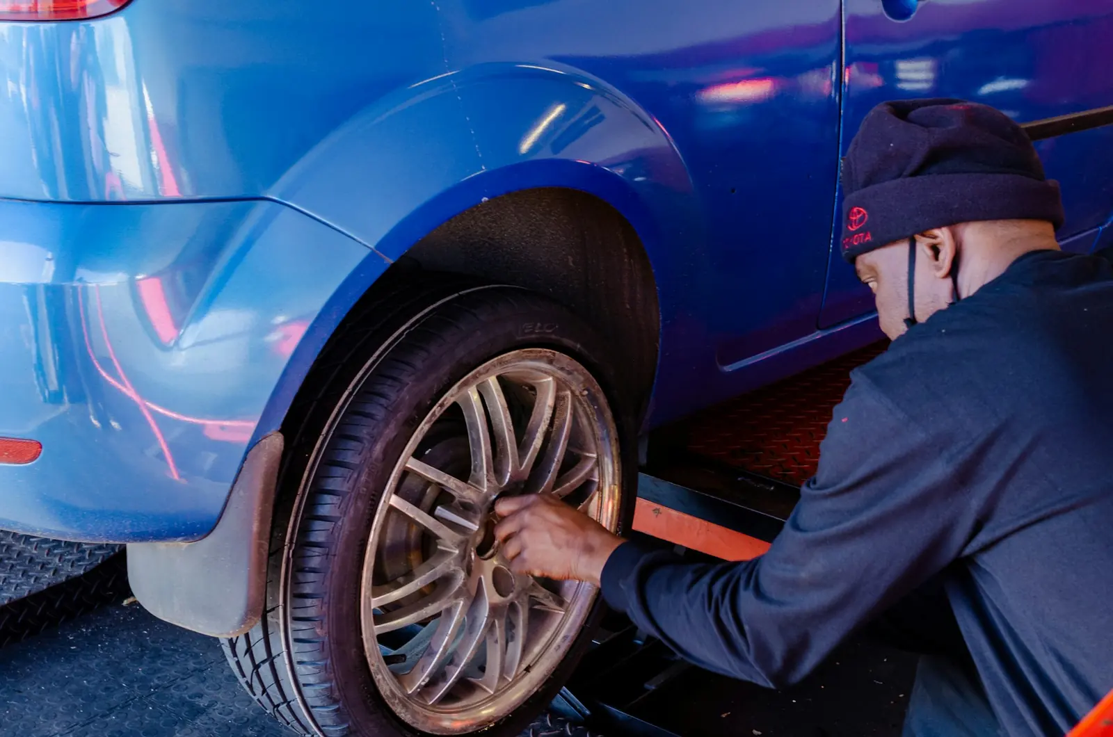 Mechanic changing a wheel on a blue car